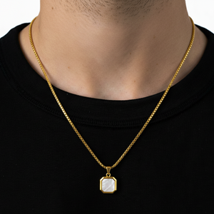 Gold necklace with a pendant on a person wearing a black shirt