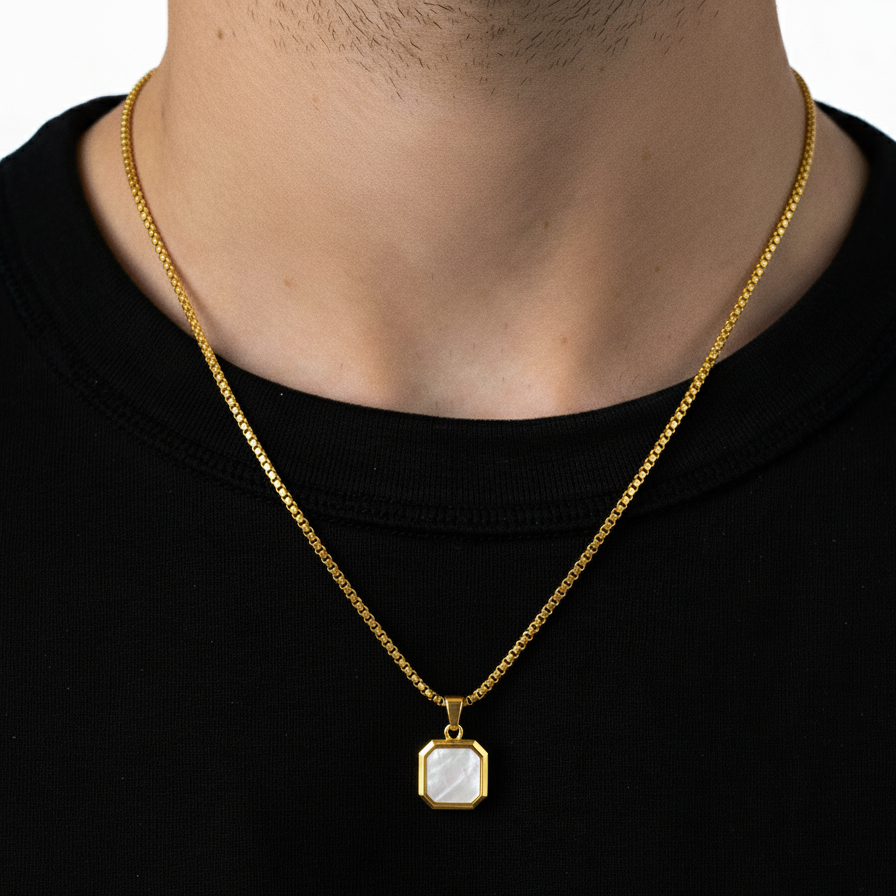 Gold necklace with a pendant on a person wearing a black shirt